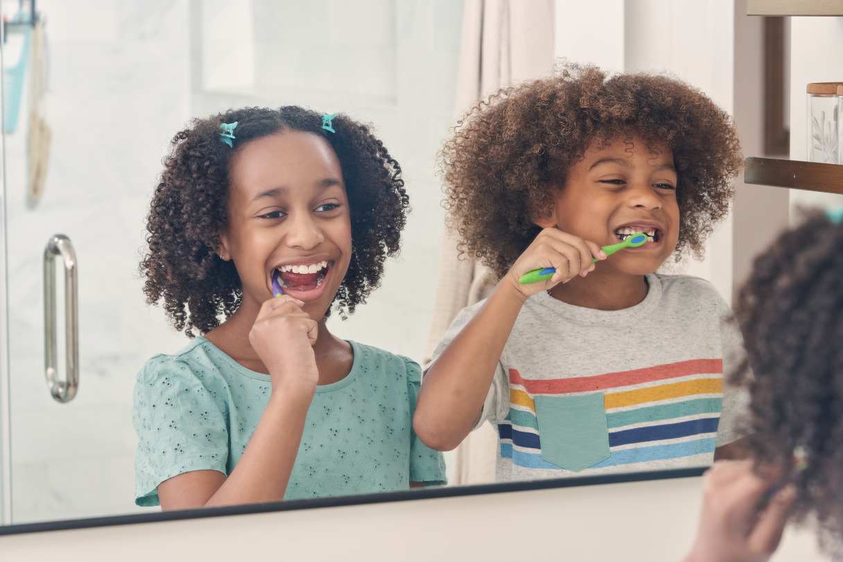Two young girls brushing their teeth together